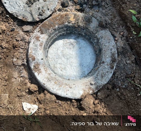פתח ביוב פתוח עם מכסה מונח בצד